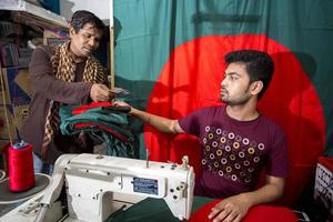 bangladesh, diciembre 09, 2017, un comprador comprando un recién cosido bangladeshi rojo verde bandera adelante de victoria mes cerca Gulistán a dhaka. foto