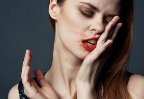 Woman with bright makeup and smeared lipstick on her face photo