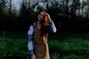 Young active woman relaxing in nature in summer and watching the sunset in the distance photo