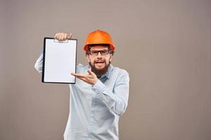 A man in a shirt with an orange hard hat engineer work documents rendering services photo