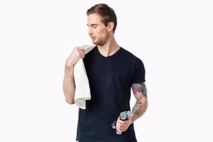 handsome male athlete with a towel on his shoulder and dumbbells in his hand photo