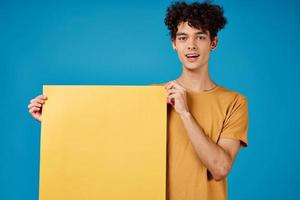 Cheerful man with curly hair yellow poster advertising blue background photo