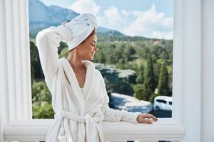 mujer en un blanco túnica en el balcón poco en verde naturaleza Perfecto soleado Mañana foto