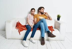 Men women with popcorn in a plate indoors on the sofa photo