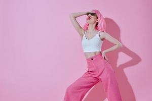 hermosa de moda niña en rosado pantalones Gafas de sol posando rosado antecedentes inalterado foto