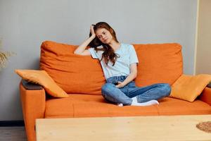 alegre mujer utilizando teléfono sentado en el sofá estilo de vida foto