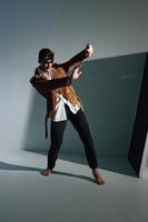 a man stands on an inclined floor indoors and covers himself with his hands from the sun photo