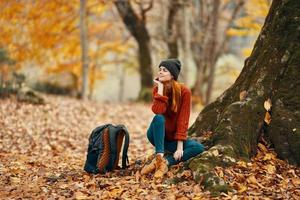 joven mujer en otoño bosque y amarillo hojas mochila modelo viaje paisaje foto