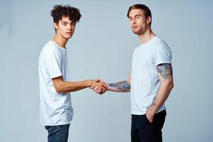 two friends hold hands in white t-shirts isolated background photo