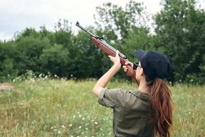 Military woman holding a gun aiming hunting green leaves photo