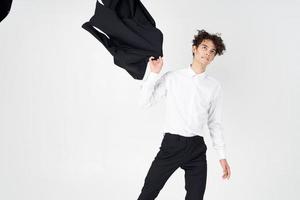 young man in classic suit with jacket in hand on light background photo