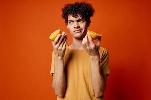 guy with curly hair oranges in hands fruit fun red background photo