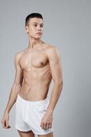 sporty man with muscular torso in white shorts isolated background photo