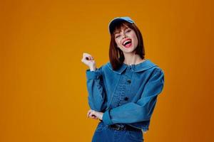 pretty woman in a cap and denim jacket posing yellow background unaltered photo