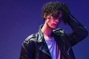 Flirted stylish curly man leather jacket eyewear looks at you posing isolated on color pink blue studio background. Cool fashion offer. Huge Seasonal Sale New Collection concept. Copy space for ad photo