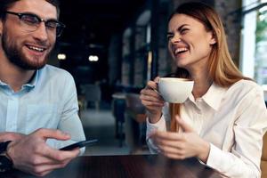 mujer Bebiendo café a el mesa siguiente a un hombre trabajo colega tecnología foto