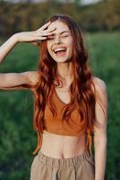 retrato de un mujer con un hermosa sonrisa en verano verde naturaleza en contra el césped, mirando fuera a el ajuste Dom. el concepto de salud y belleza foto