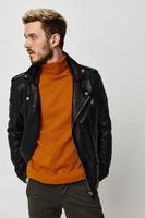 blond man in orange sweater and leather jacket looking to the side cropped view photo