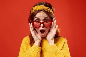 woman in yellow sweater wearing red glasses headband fashion red background photo