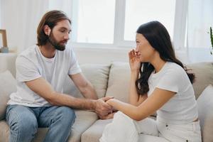 An Asian woman is sad and crying with her male friend at home. Stress and misunderstanding in a relationship between two people and supporting each other's mental and emotional well-being photo