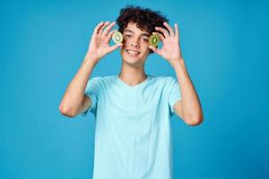 Cheerful guy with curly hair kiwi fruit blue background photo