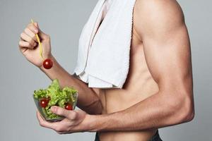 sporty man with a white towel on his shoulders a plate of salad healthy food snack photo