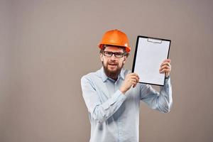 un hombre en un camisa con un naranja difícil sombrero ingeniero trabajo documentos representación servicios foto