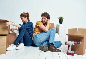man and woman sitting on the floor with their backs to each other renovation work moving a flower in a pot photo