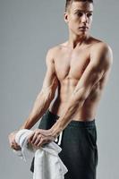 sporty man on muscular torso towels in hands cropped view gray background posing photo