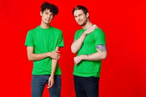 Cheerful friends in green t-shirts gesturing with hands emotions photo