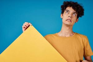 guy with curly hair with yellow poster grimace blue background photo