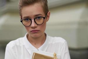 student with glasses walking around the city with a book education photo