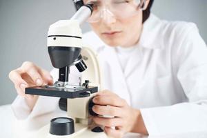 un científico en un blanco Saco mirando mediante un microscopio de cerca laboratorio foto