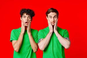 alegre amigos en verde camisetas sostener en a el cara de emoción foto