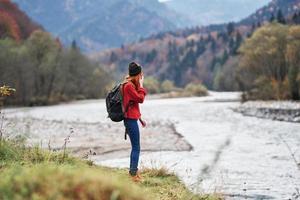 young woman with backpack in the mountains autumn travel tourism landscape shallow water river photo
