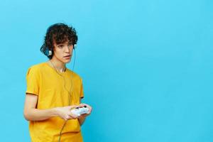curly guy plays with joystick in yellow t-shirts technologies photo