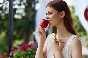 bonito mujer participación un café taza en pie en el parque a verano verano día foto