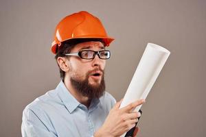 Male engineer with glasses in orange paint. Professional blueprints in hands photo