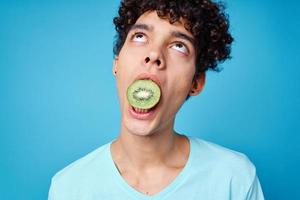 hermoso hombre con kiwi Rizado pelo en su boca recortado ver en azul antecedentes foto