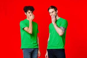 two friends cover their hand face emotions displeasure red background photo