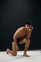 atlético hombre en oscuro bragas con desnudo muscular cuerpo es arrodillado foto