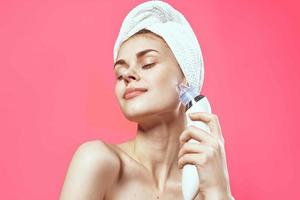 woman with towel on head cleaning skin naked shoulders pink background photo