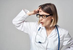 médico en un médico vestido con un estetoscopio alrededor su cuello perplejo Mira gris antecedentes foto