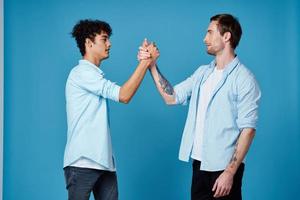 Happy friends in identical shirts shake hands on a blue background communication photo