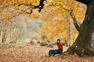 travel tourism woman model in autumn forest falling leaves landscape nature park photo