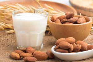 Almond milk in glass with almonds on wooden table photo