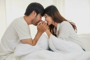 Happy young asian couple embracing, teasing, playing cheerfully in bed at home, romantic time to enhance family bonding. family concept. photo