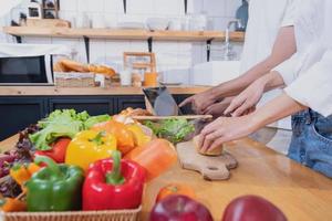 joven asiático Pareja Cocinando con frutas y vegetales y utilizando ordenador portátil en el cocina a cocinar comida juntos dentro el familia felizmente, familia concepto. foto