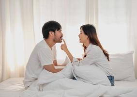 Happy young asian couple embracing, teasing, playing cheerfully in bed at home, romantic time to enhance family bonding. family concept. photo