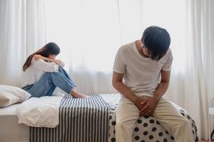 The husband is unhappy and disappointed in the erectile dysfunction during sex while his wife sleeping on the bed. Sexual Problems in Men, The concept of erectile dysfunction according. photo